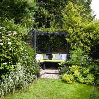 Pretty garden, grass lawn, black arbour frame, bench seating, cushions. Home owned by Elaine Wallace,