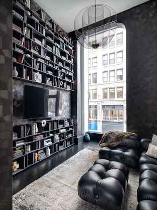 dark toned living space with dark wallpaper, black book shelves and large window