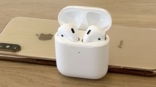 AirPods 2 in open charging case with iPhone XS