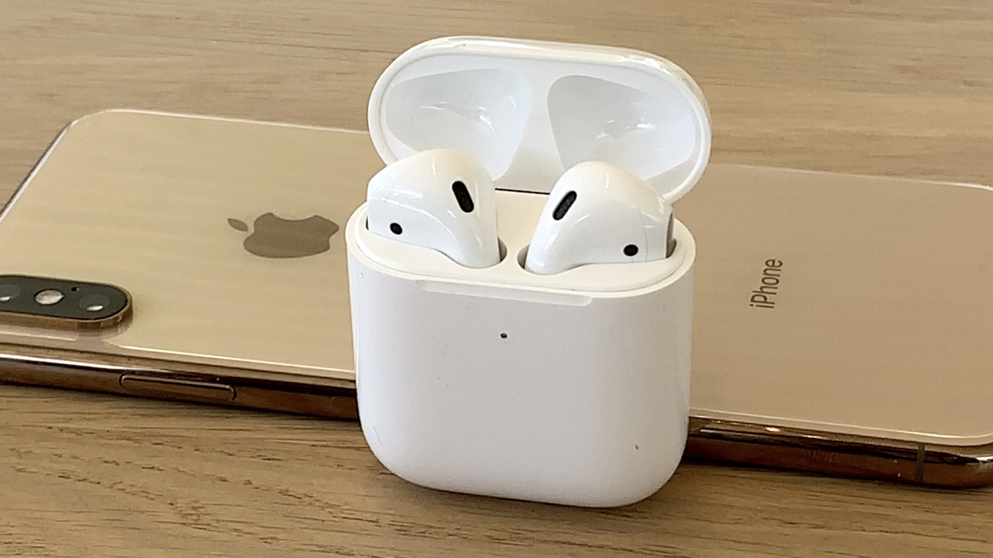 AirPods 2 dalam wadah pengisi daya terbuka dengan iPhone XS