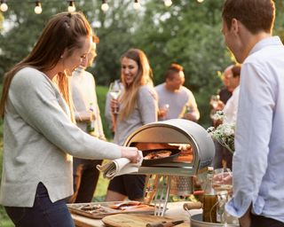 People gathered round a pizza oven in a garden