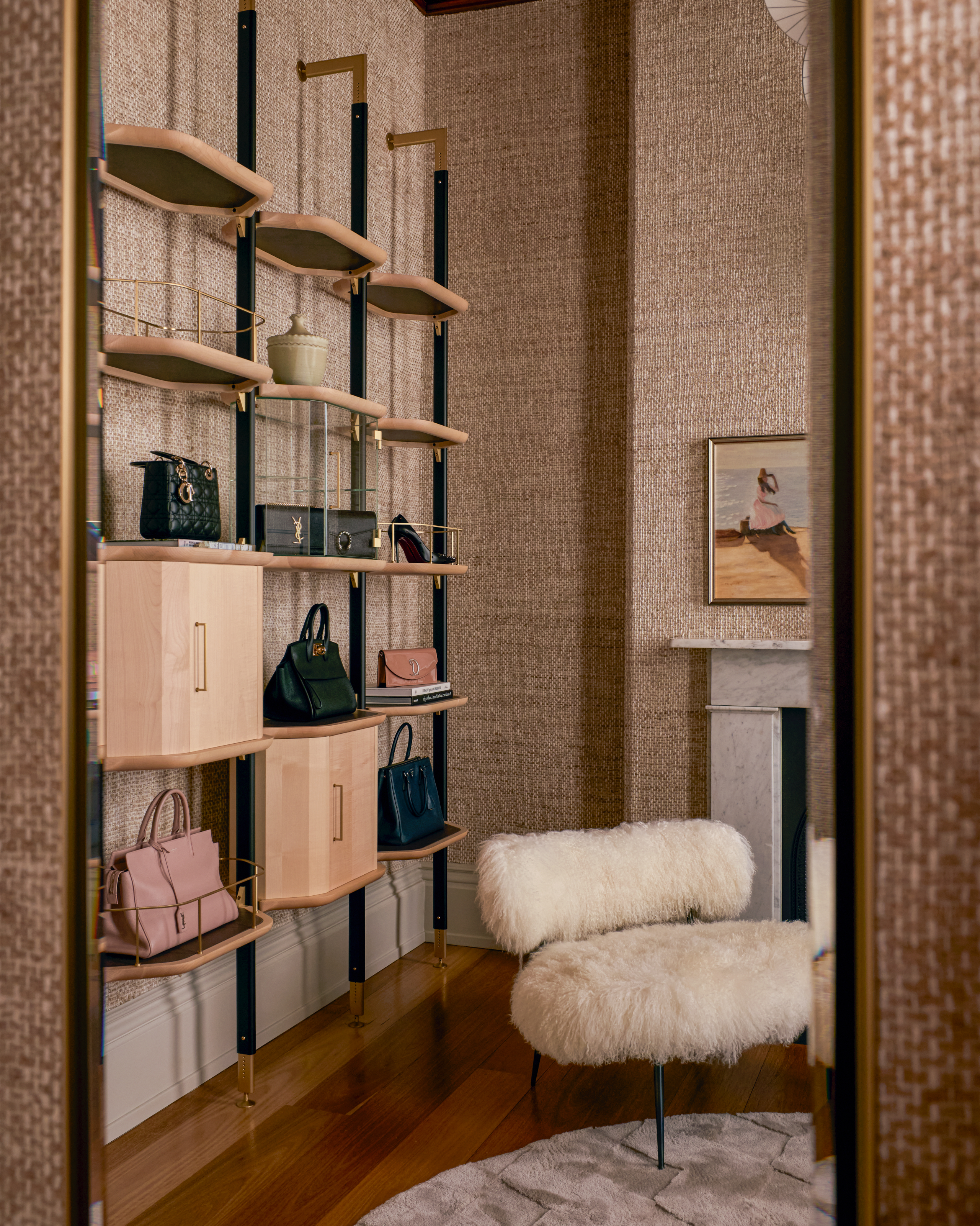 Dressing room with wall bookcase displaying handbags with a long-pile sheepskin style accent chair