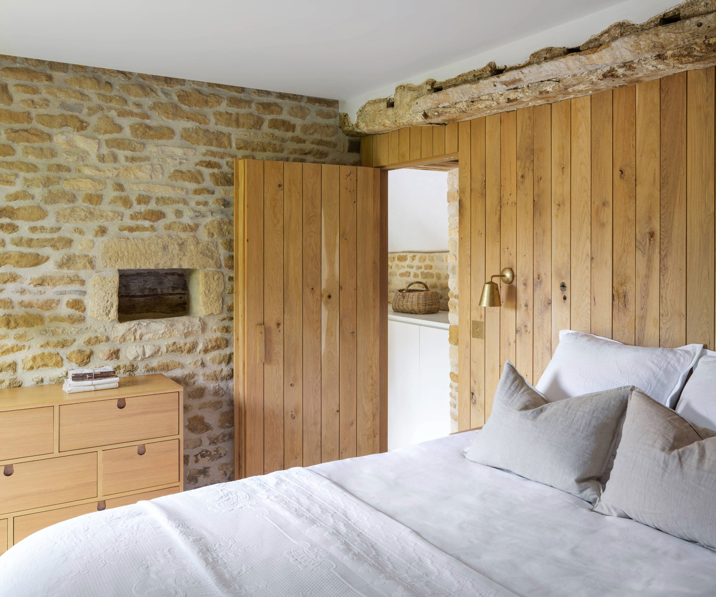 Bedroom with exposed brick wall and wooden cladding behind the bed and door