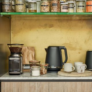 Kettle, coffee machine, cups and coffee supplies on countertop