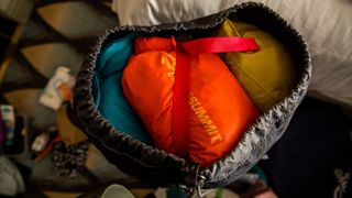 A close-up of the top of a hiking bag, showing a bright orange Sea to Summit Lightweight Dry Bag packed at the top.