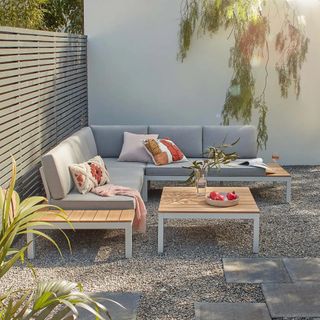 A contemporary garden corner sofa with wood frame with grey cushions