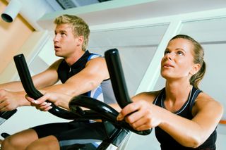 A couple exercises together at a gym.