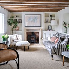 Cottage-style living room with woolen carpet, a log burner, and a striped sofa with accent chairs around it
