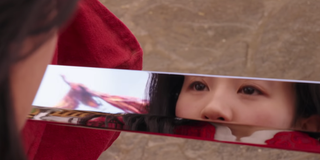 Mulan stares into her sword blade as a phoenix flies in its reflection.