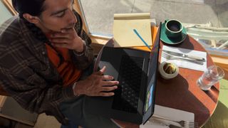 En man sitter vid ett cafébord och använder en 16-tums MacBook Pro med M3-chippet.