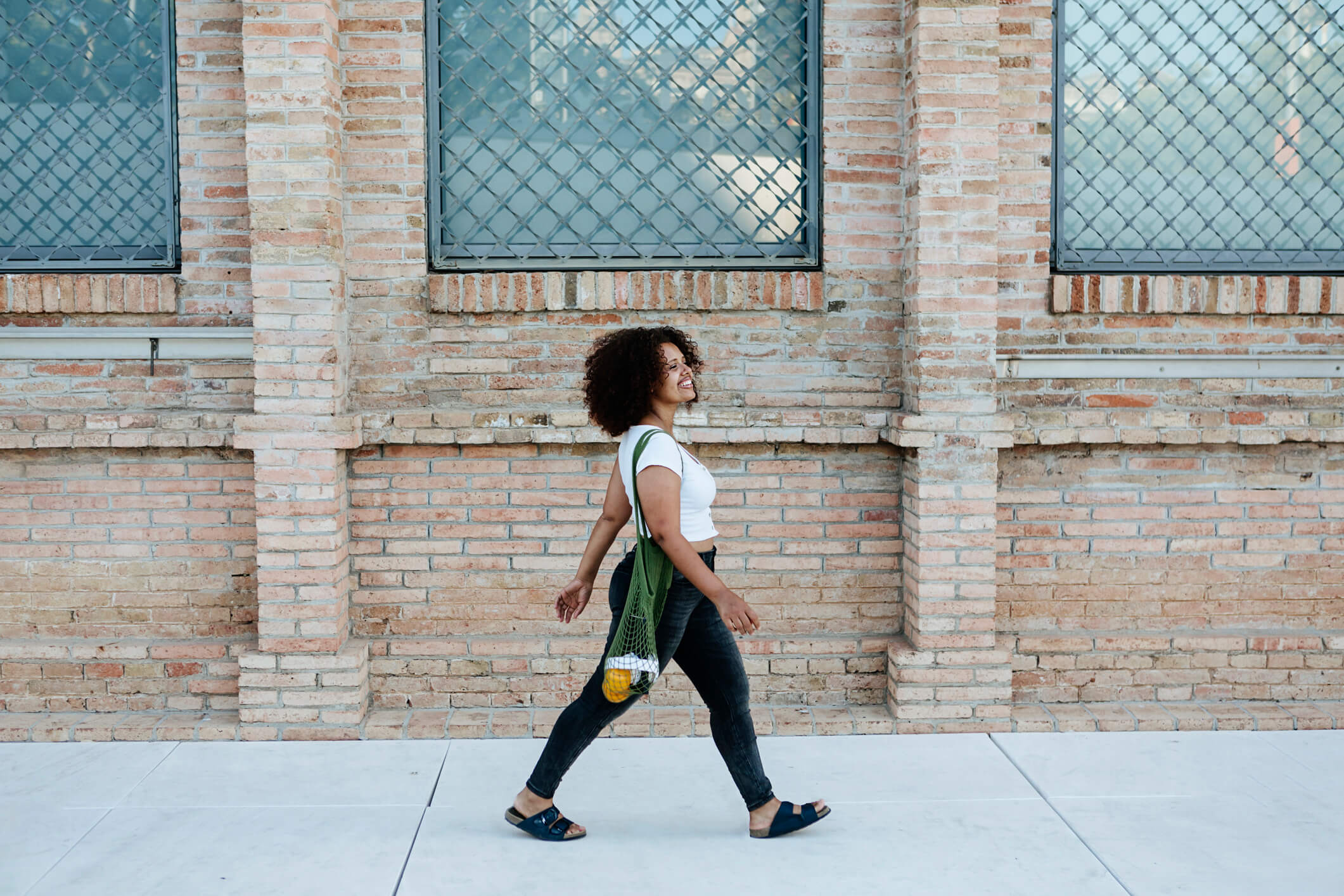 A happy woman walking outside near a brick building.