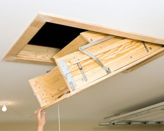 Open attic hatch and a hand pulling it down