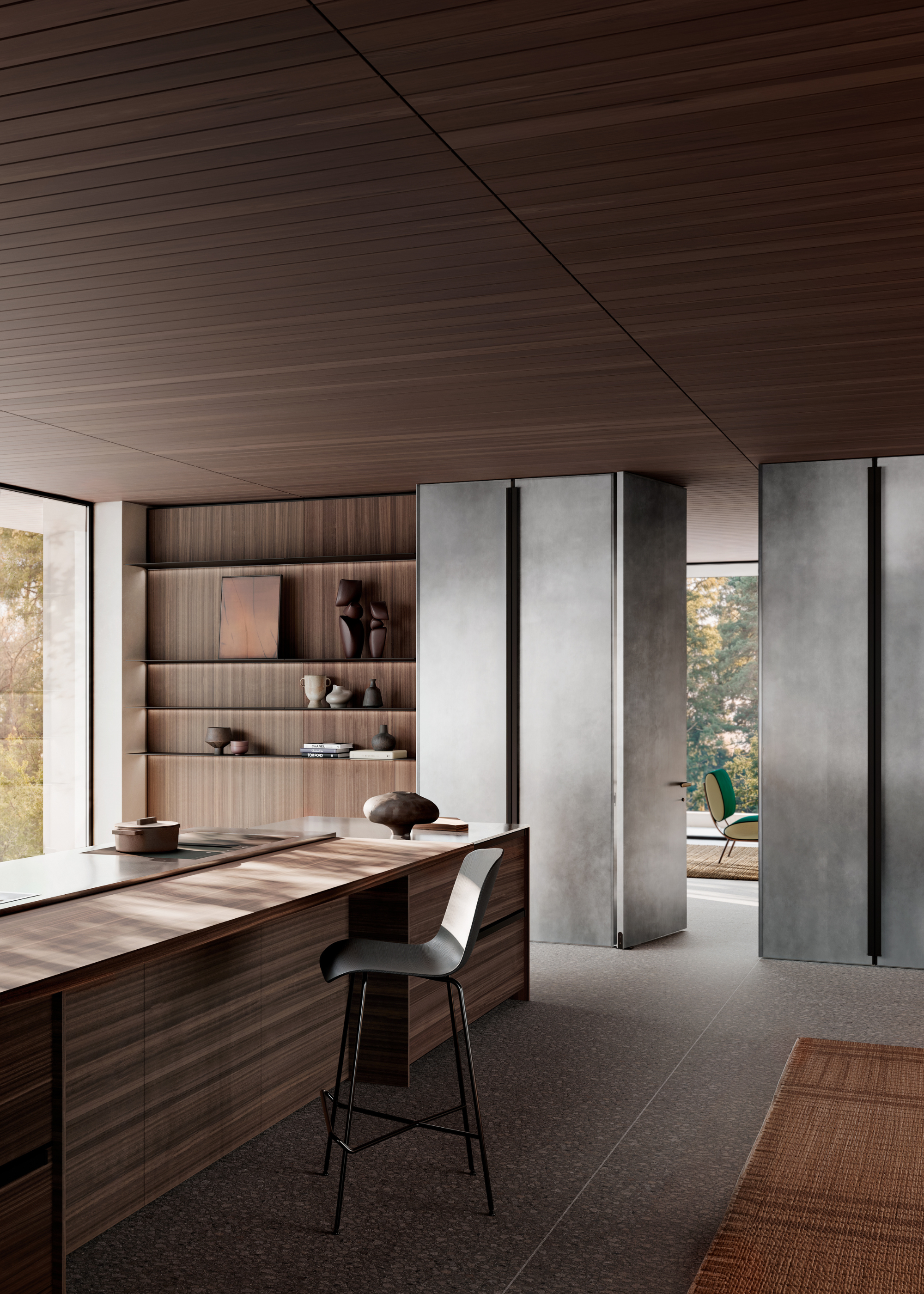 A kitchen with a wood island, a single stool, a wall of shelves with ceramics, and brushed metal doors