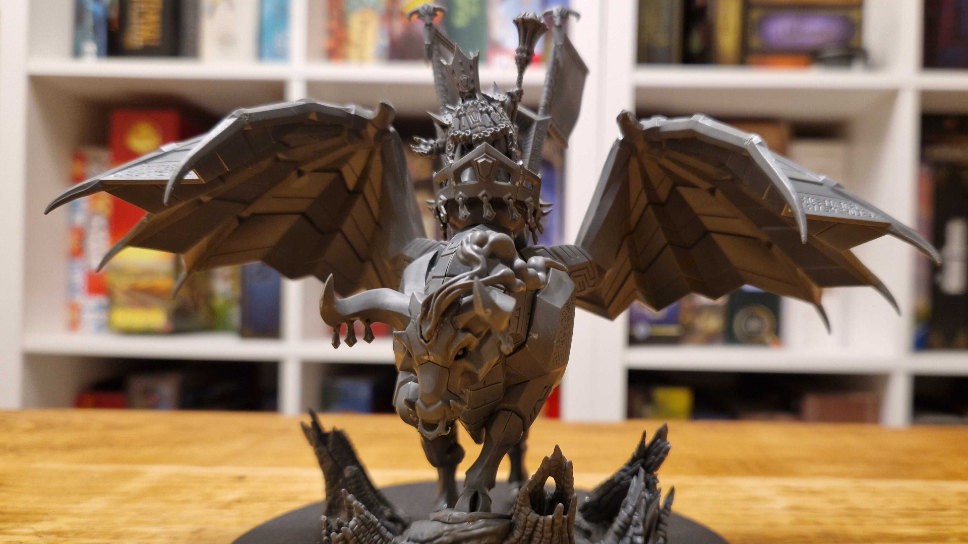 Daemonsmith on Infernal Taurus model on a wooden table, with a board game storage unit in the background