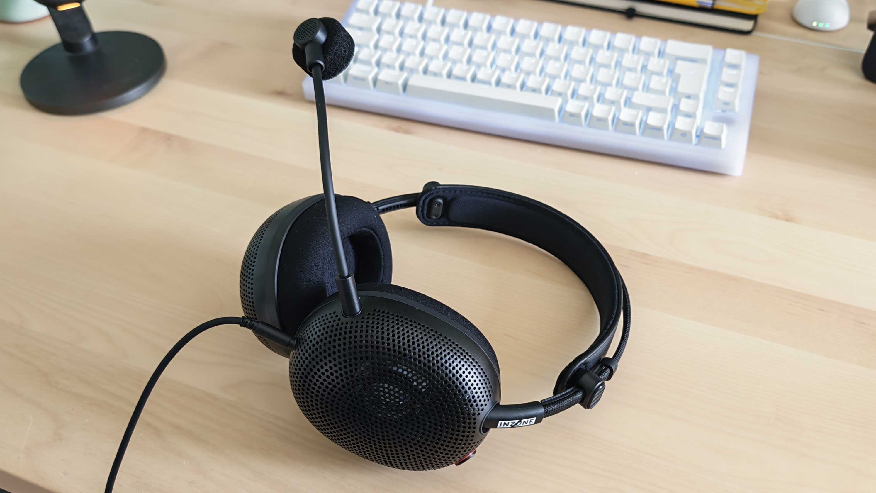 A photo of the Inzone H6 Air gaming headset positioned above a wooden desktop surface.