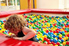 A little girl playing in a ball pit now that soft play centres are to open