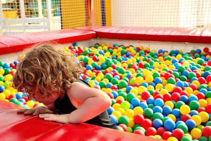 A little girl playing in a ball pit now that soft play centres are to open