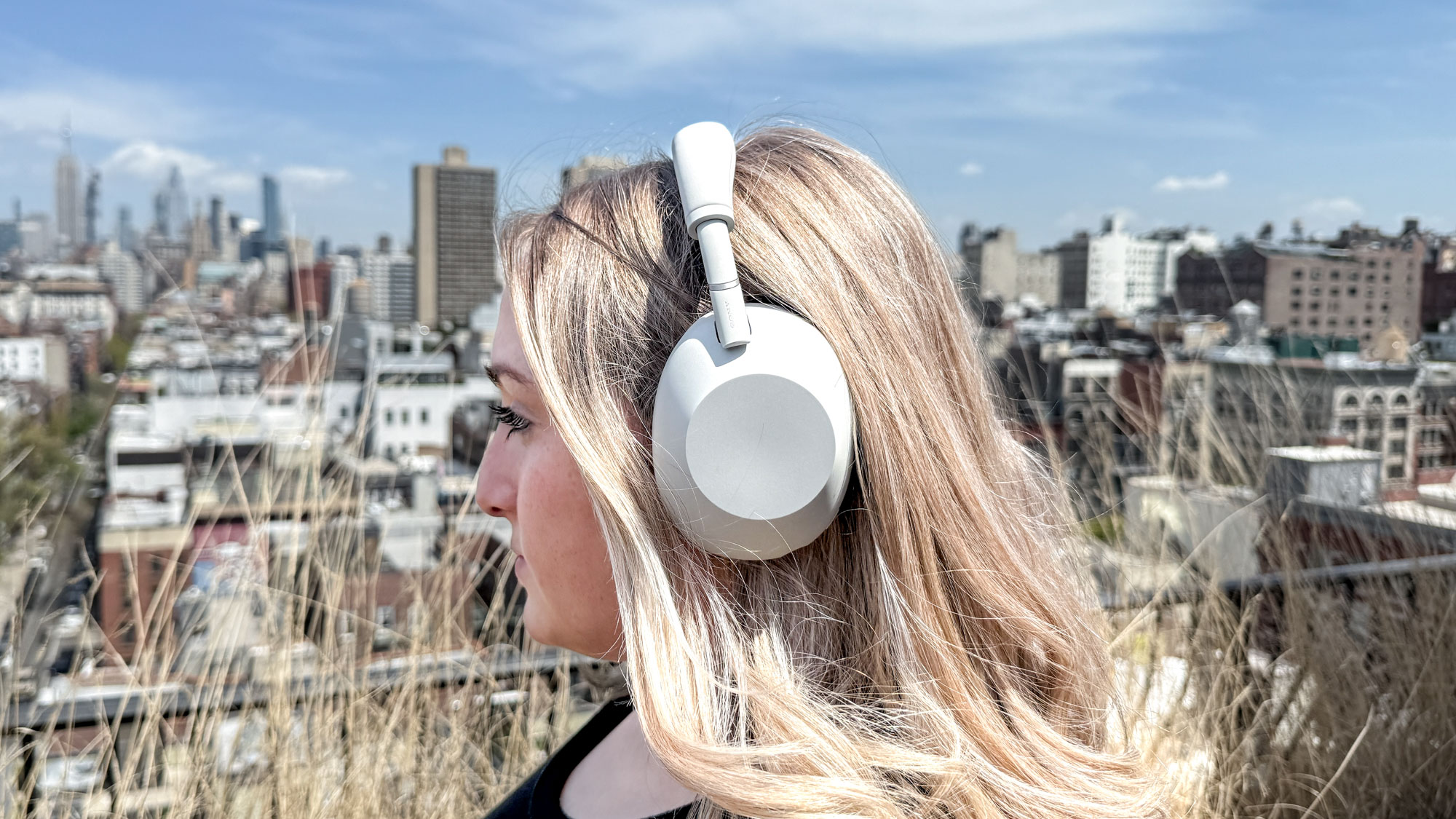Side view of a woman wearing white Sony WH-1000XM6 noise-cancelling headphones