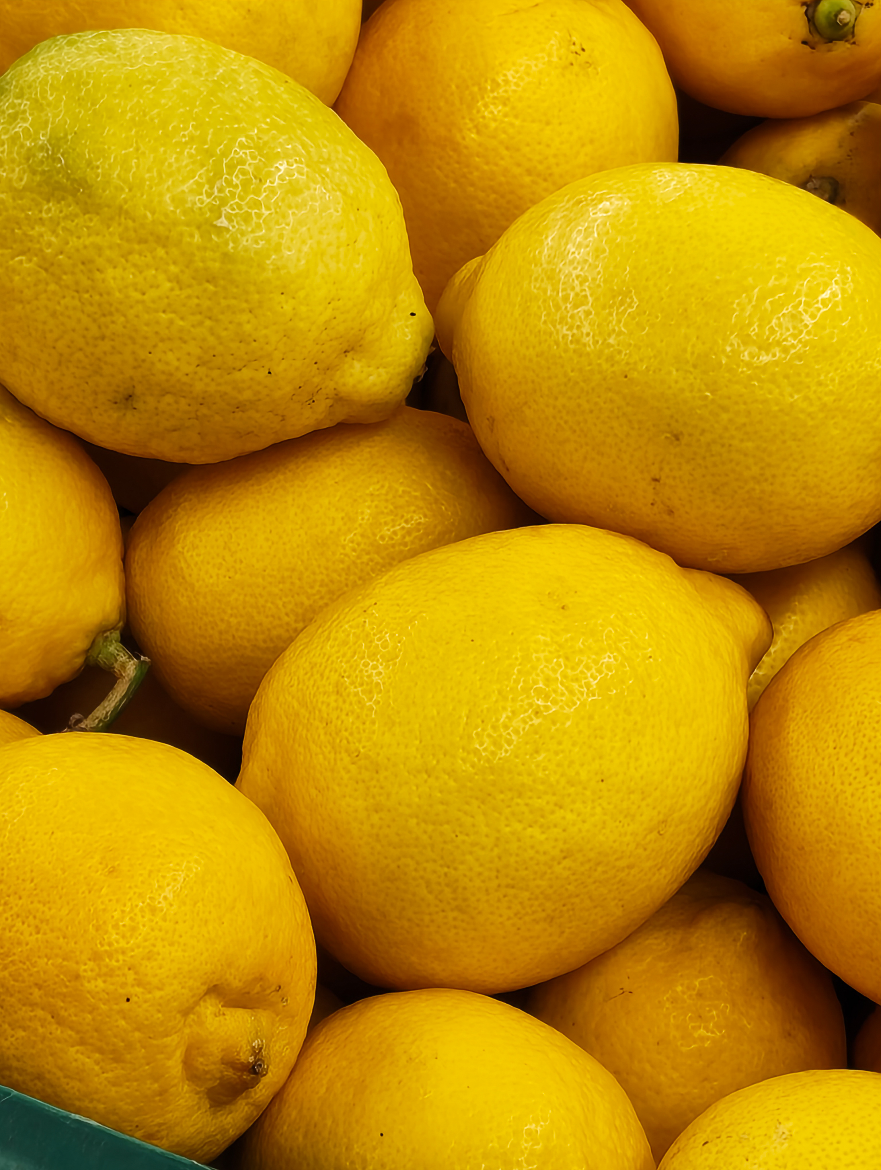 Close-up of bright yellow lemons stacked together in a market crate, photographed with the Nothing Phone (4a).