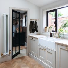 Kitchen with cream coloured cabinets, window, door to bathroom