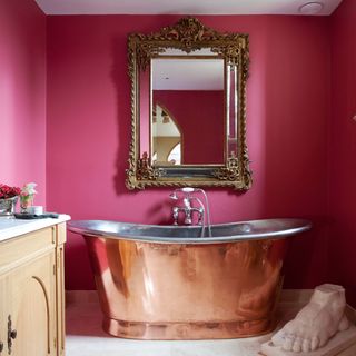 pink bathroom with copper bathtub and mirror
