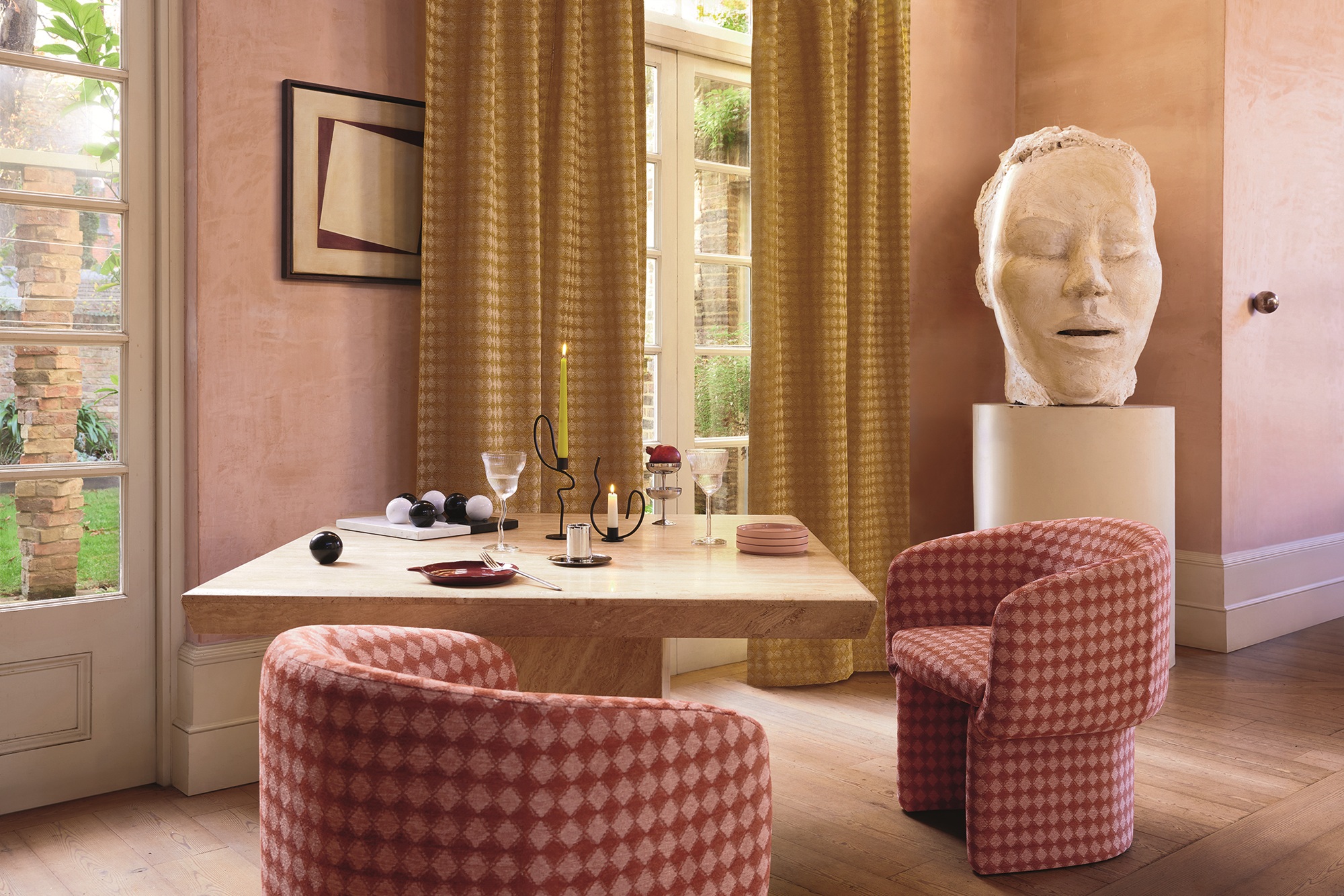 a dining table with glasses on with patterned chairs and a large head sculpture