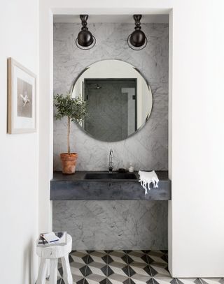 grey bathroom with floating sink, circle mirror and patterned floor tiles