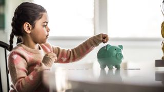 Young girl putting money in piggy bank