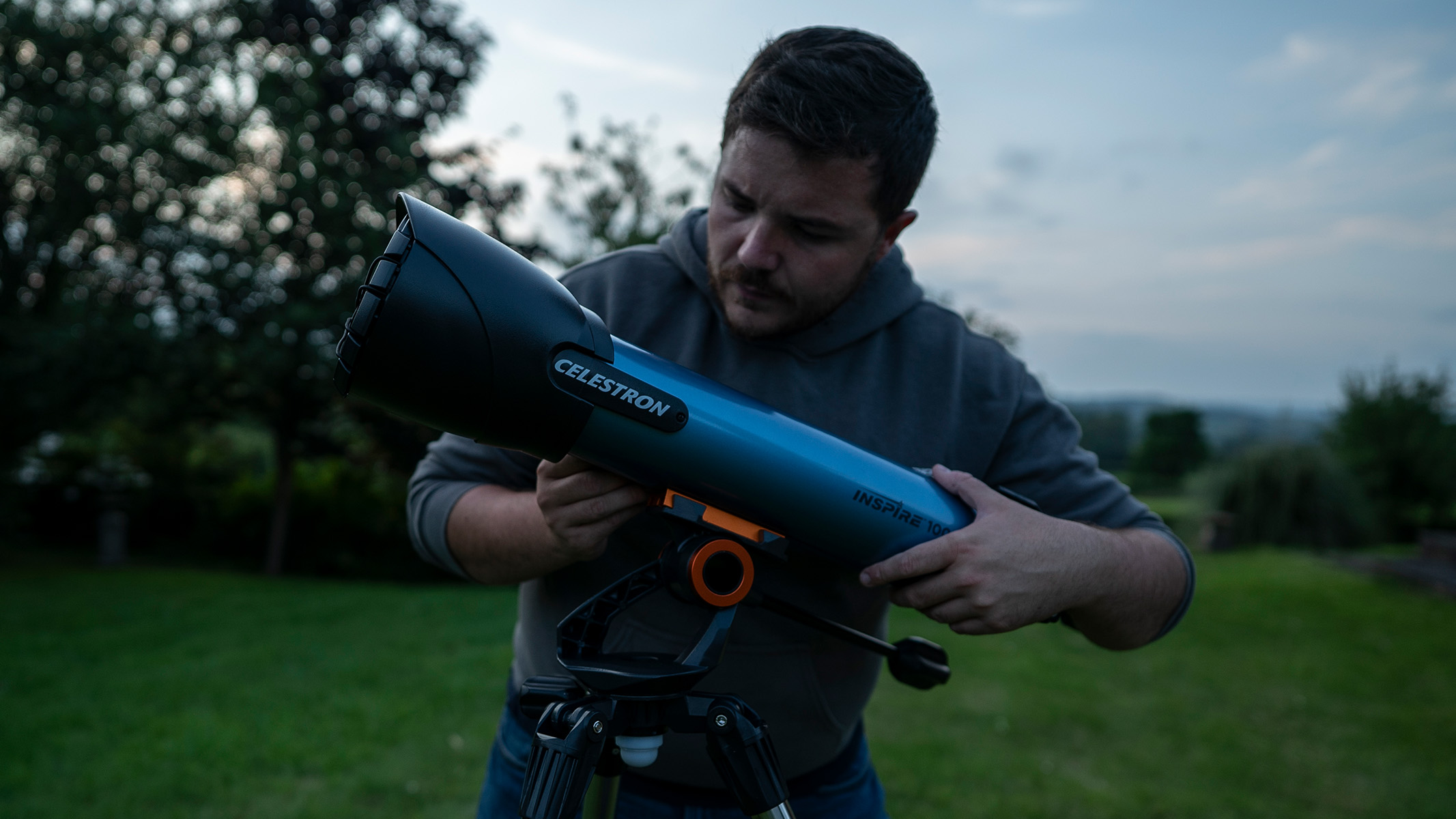 Man setting up the Celestron Inspire 100AZ in a field