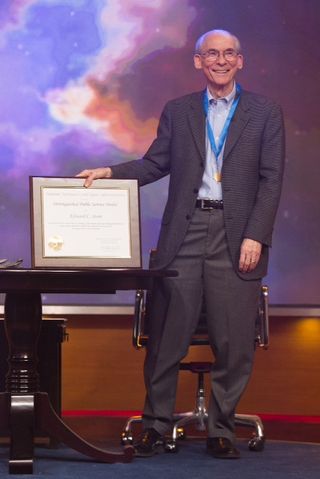 Ed Stone, Project Scientist for NASA's Voyager mission since 1972, stands with his Distinguished Public Service Medal and accompanying certificate. He received the award on the talk show The Colbert Report on Dec. 3, 2013.