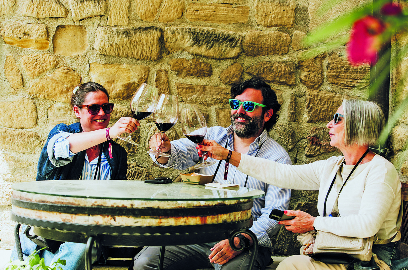 three people drinking wine around a table