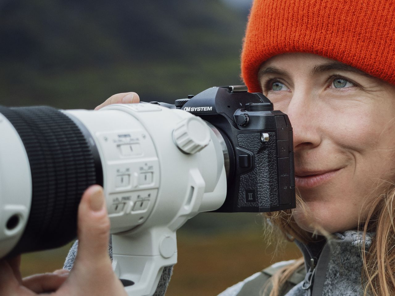 Photographer holding the OM System OM-1 II with M.Zuiko 150-600mm F5.0-6.3 IS lens attached