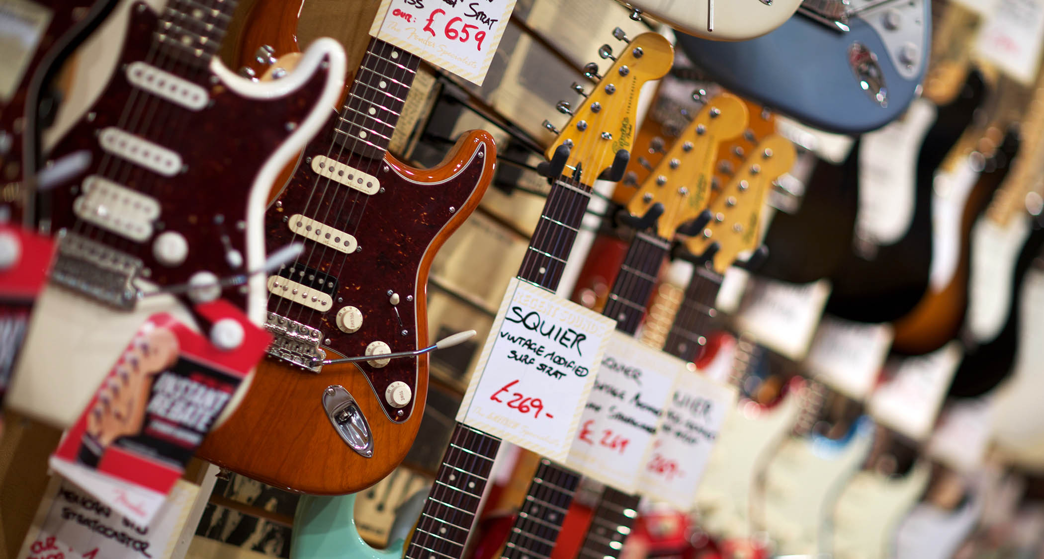 A close up of a rack of Stratocasters in a guitar store.
