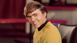 a young man on a sci-fi set in a gold uniform