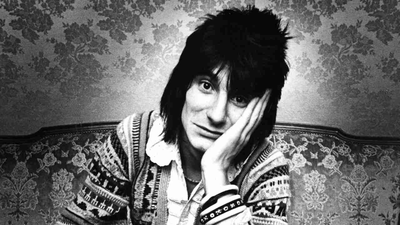 Ronnie Wood posing for a photograph on a couch in 1976