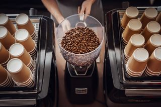 Barista operating grinder with coffee beans - stock photo
