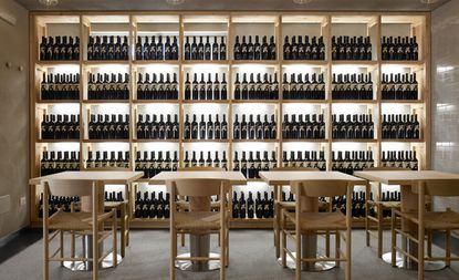 Tables & chairs in front of wall to floor shelves of wine