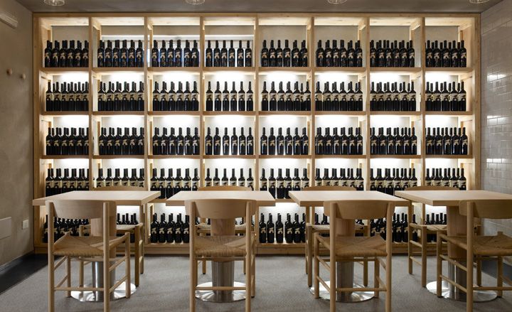 Tables &amp; chairs in front of wall to floor shelves of wine