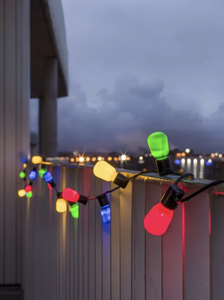 red, blue, green and yellow lights wrapped around a white fence