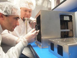 The world's first 3D printer headed for space, built by Made In Space, is assembled for its launch aboard a SpaceX Dragon spacecraft. Made In Space team members Mike Snyder and Jason Dunn are shown performing the work.