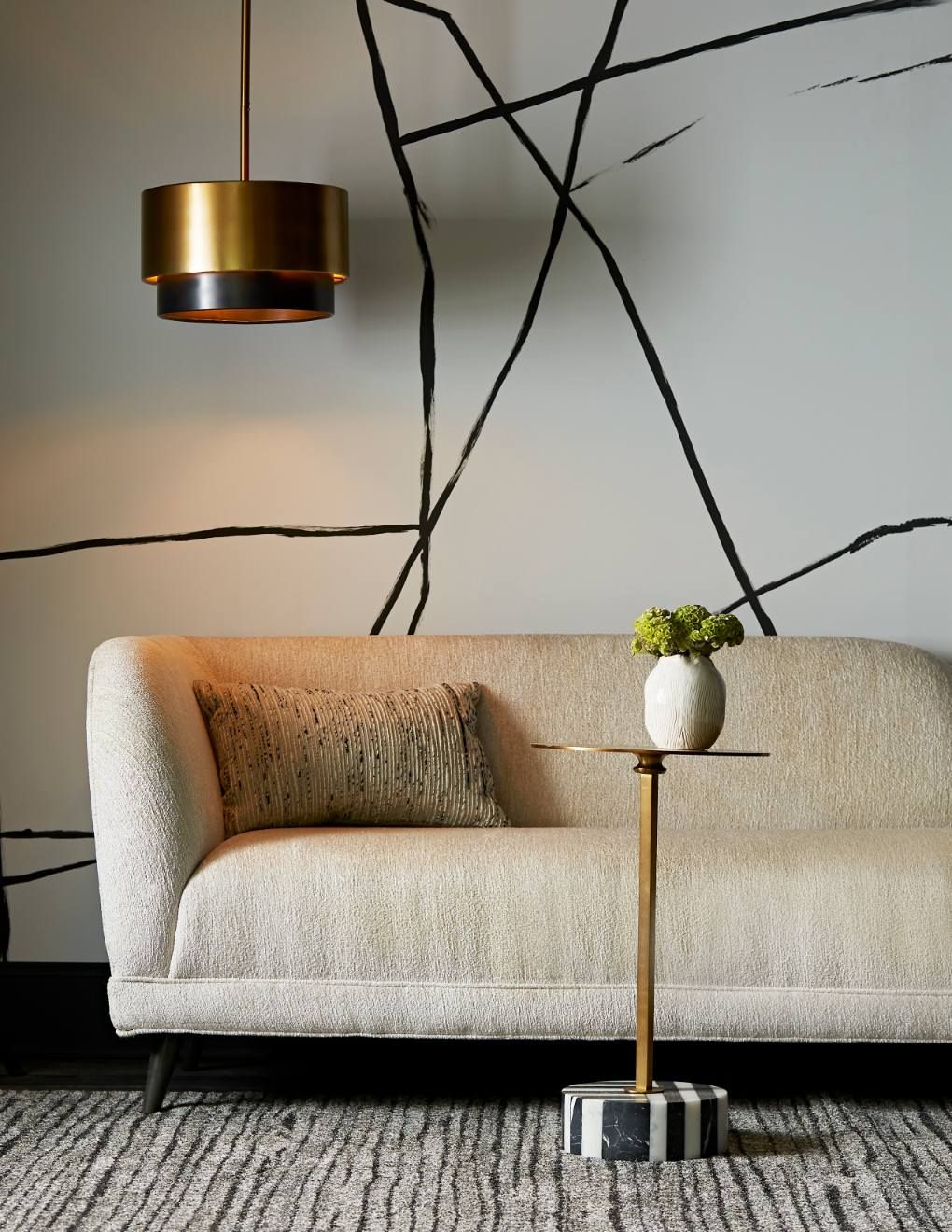 A cream couch with a black and white wallpaper