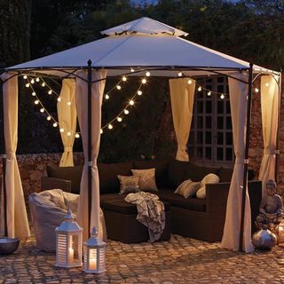 garden area with gazebo and curtains with candle lantern