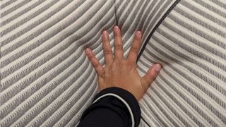 The image shows Tom's Guide's lead tester laying her hand on the surface of the Beautyrest Black Luxury Foam Pillow