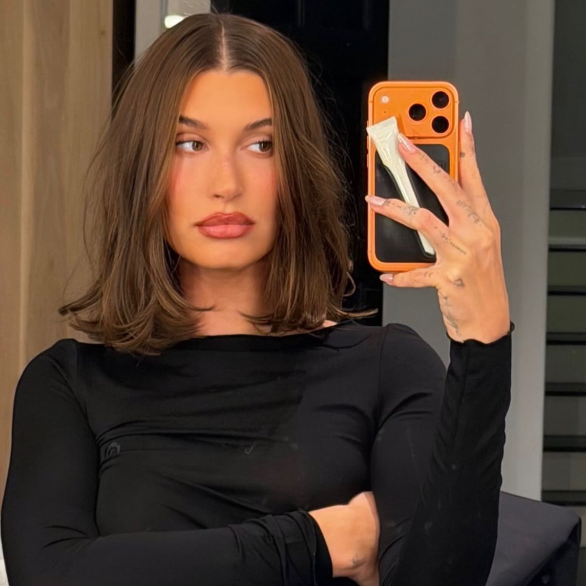 A photo of Hailey Bieber with a lob haircut, taking a selfie in the mirror