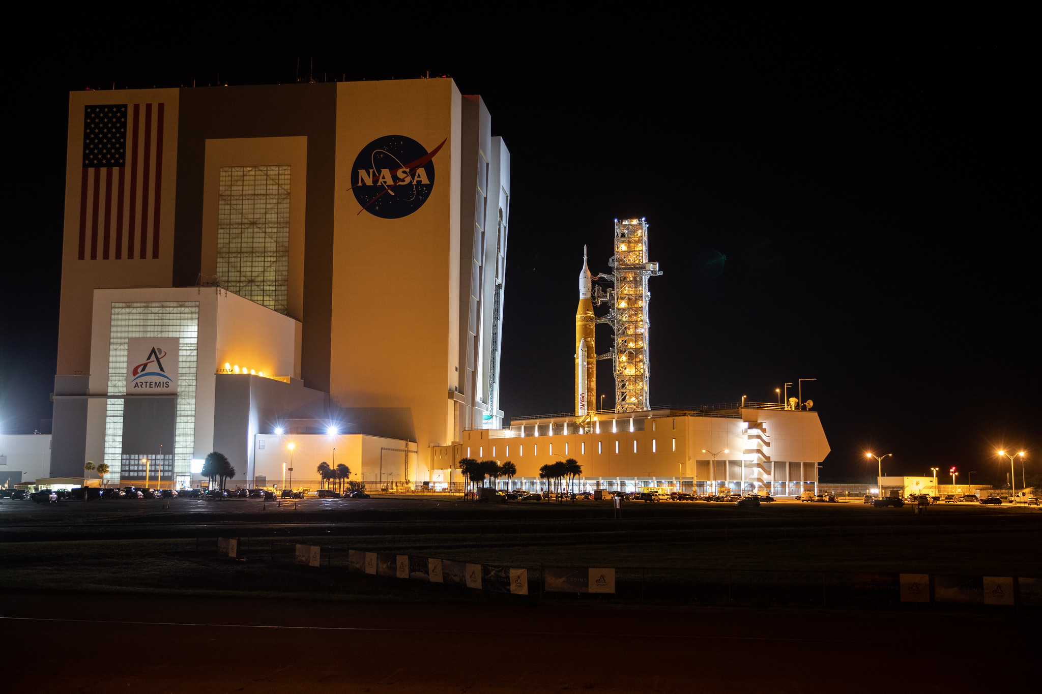 NASAs Artemis 1-månerakett – båret på toppen av byråets belte-transporter 2 – ruller ut av Vehicle Assembly Building ved byråets Kennedy Space Center i Florida 6. juni 2022, og begynner den 4,2 mil lange (6,8 kilometer) reisen til Launch Complex 39B . 
