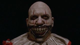 Close-up of Twisty The Clown without hat standing outside carnival entrance in American Horror Story: Freak Show