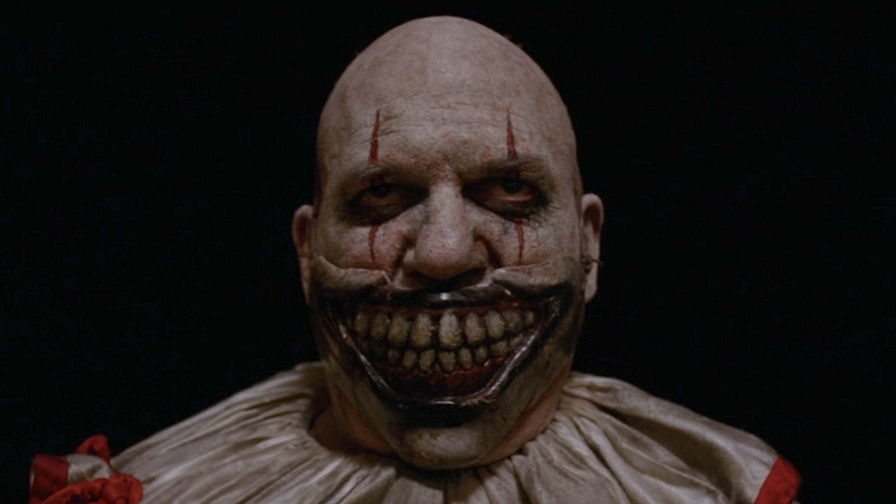 Close-up of Twisty The Clown without hat standing outside carnival entrance in American Horror Story: Freak Show