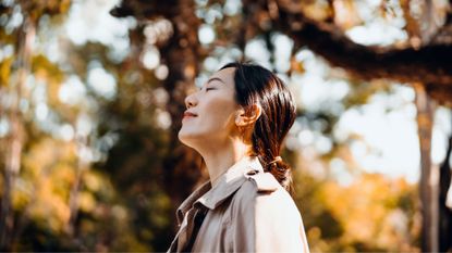 Woman looking up into autumnal trees