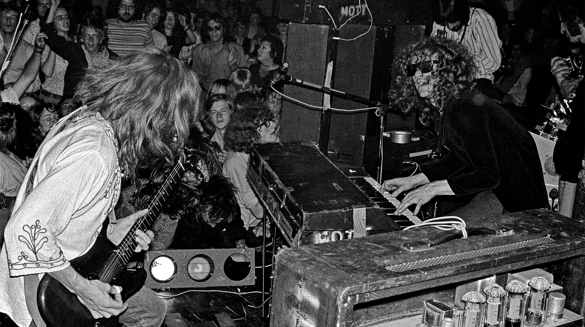Mick Ralphs and Ian Hunter of Mott The Hoople perform on stage, with the audience cheering behind, at The Royal Albert Hall, London on July 8 1971.