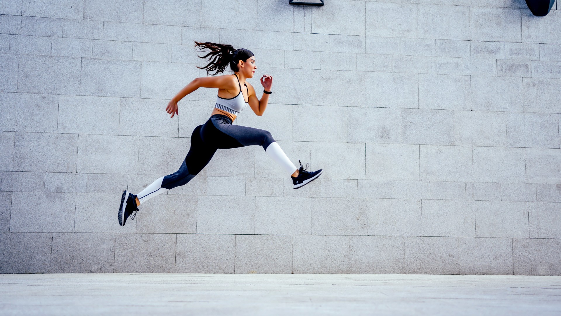 Woman running against a grey background outdoors